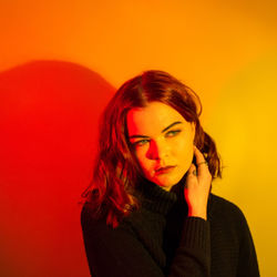 Portrait of beautiful young woman against orange background