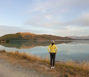 Rear view of man standing on lake against sky