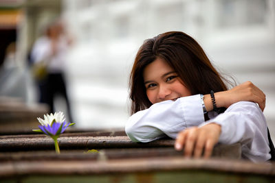 Portrait of teenage girl with flower sitting outdoors