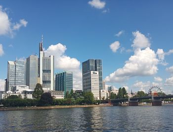 Buildings by river against sky