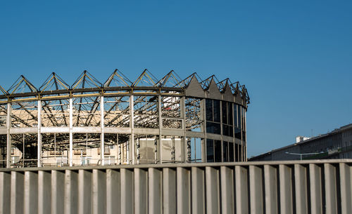 Low angle view of amusement park against clear blue sky