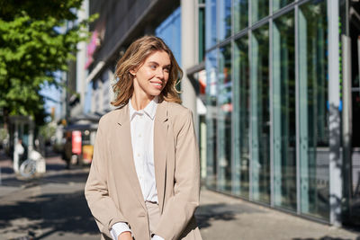 Portrait of young woman standing in city