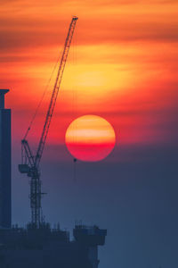 Silhouette crane against sky during sunset