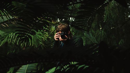 Portrait of man photographing through tree