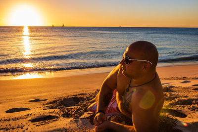 Man on beach against sky during sunset