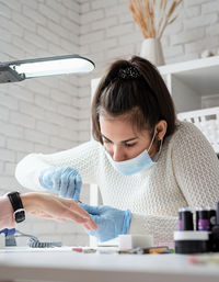 Young woman wearing glove and mask working at salon