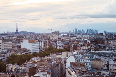 Paris cityscape with eiffel tower and defense district at sunset in a cloudy day