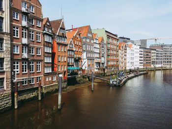 Buildings by canal against sky in city