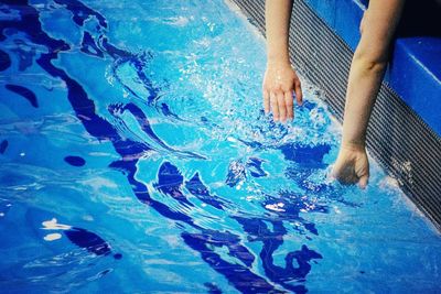 Low section of man swimming in pool