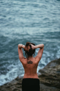 Rear view of young woman standing at beach