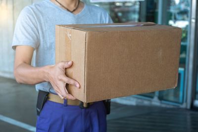 Midsection of man holding paper while standing against wall