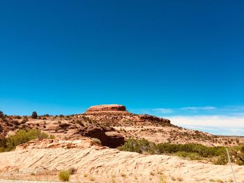 Rock formations on landscape against clear blue sky