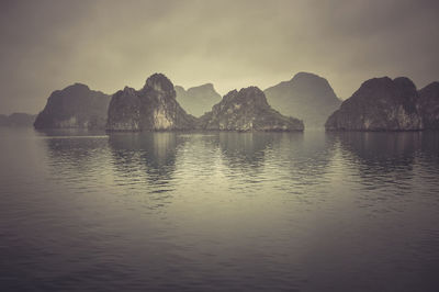 Mountains in sea against sky during sunset