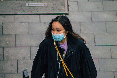 Portrait of young woman standing against brick wall