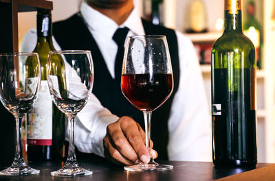 Midsection of man drinking glasses on table