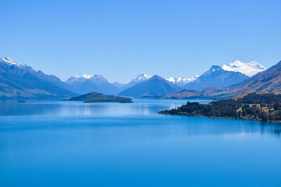 Scenic view of lake and mountains against blue sky