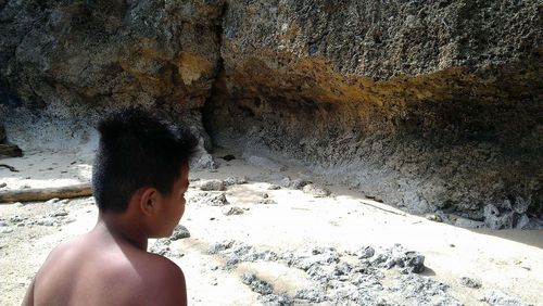 Boy standing on rock at beach