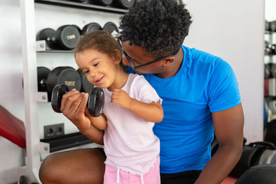 Father teaching daughter to lift dumbbell