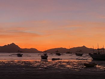 Silhouette sailboats moored on sea against sky during sunset