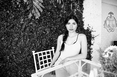 Portrait of woman sitting at table against plants in yard