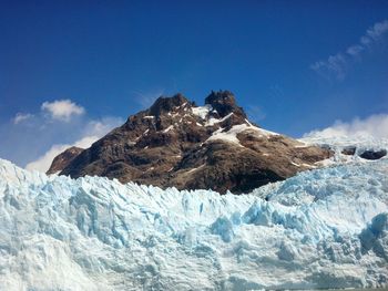 Scenic view of glacier by mountain against sky