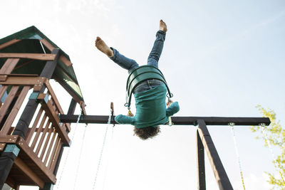 Low angle view of girl swinging against clear sky