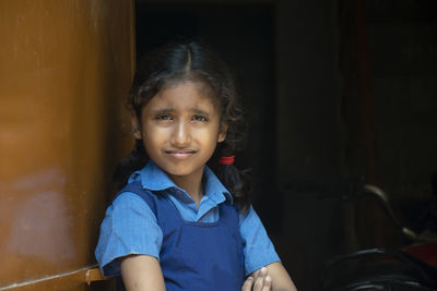 Portrait of girl wearing school uniform standing by wall