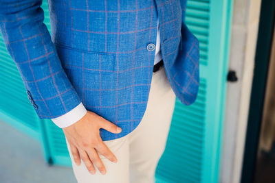 Midsection of man standing against blue wall