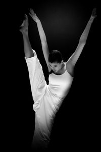 Midsection of woman dancing against black background