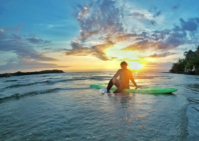 Man on beach against sky during sunset