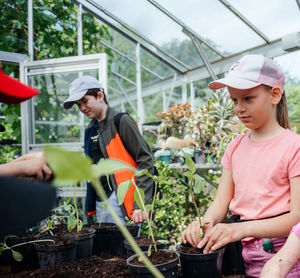 Young gardeners transplanting plants in greenhouse