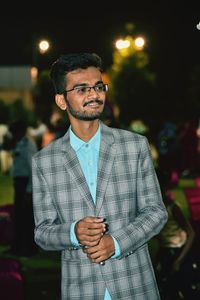 Smiling teenage boy wearing checked blazer at night