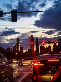 Cars on street by buildings against sky in city