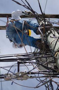 Low angle view of man standing on electricity pole