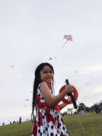 Portrait of smiling young woman standing against sky