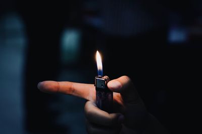 Close-up of hand holding burning cigarette lighter at night