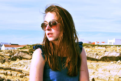 Portrait of smiling young woman standing against sky