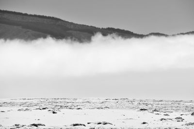 Scenic view of snow covered land and sea against sky