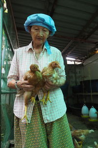 Senior woman holding chickens at farm