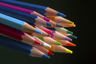 Close-up of colored pencils on table against black background
