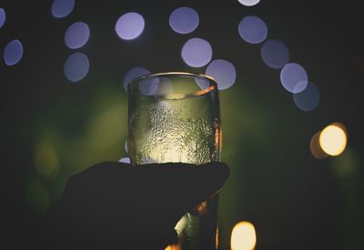 Close-up of wine glass against illuminated blurred background