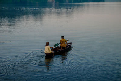 Rear view of men sitting on boat in lake