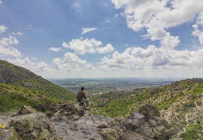 Scenic view of man sitting on mountain 