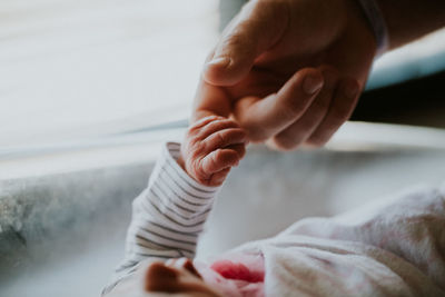 Close-up of baby holding hand on bed