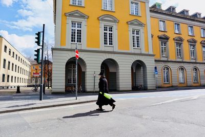 Rear view of woman walking on street against buildings in city