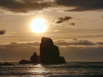 Sharp silhouette of a cliff against sunset. sea waves break on the rocks. talisker bay, scotland.