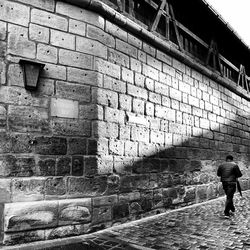 Rear view of man walking on alley amidst buildings