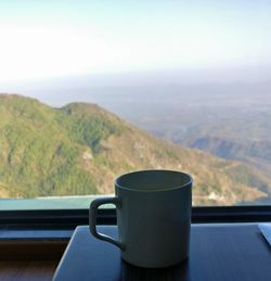 Coffee cup on table against mountains