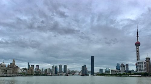 City at waterfront against cloudy sky