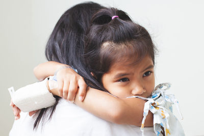 Mother carrying sick daughter against wall in hospital